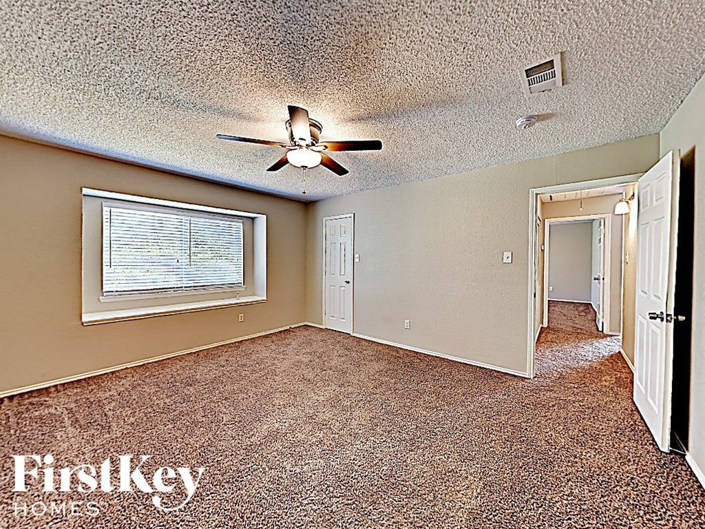 an empty living room with a ceiling fan and a window