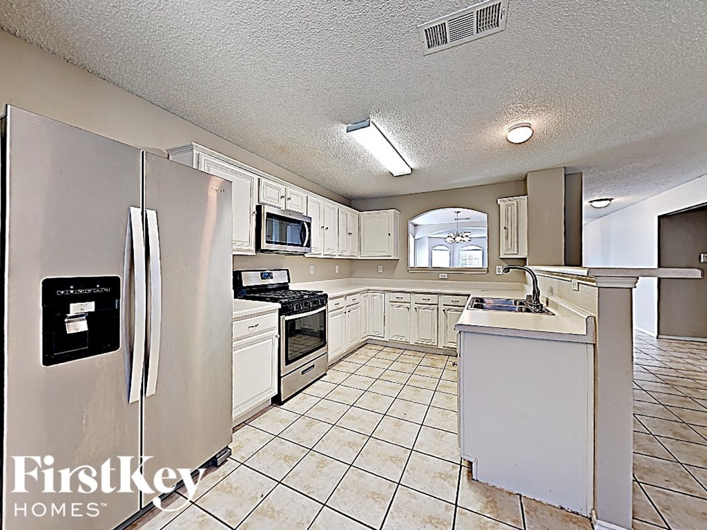 an all white kitchen with white cabinets and stainless steel appliances