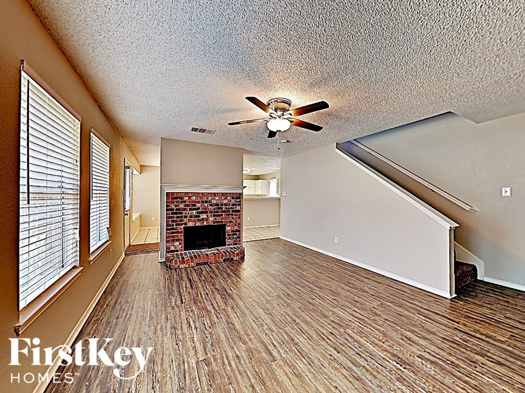 an empty living room with a fireplace and a ceiling fan