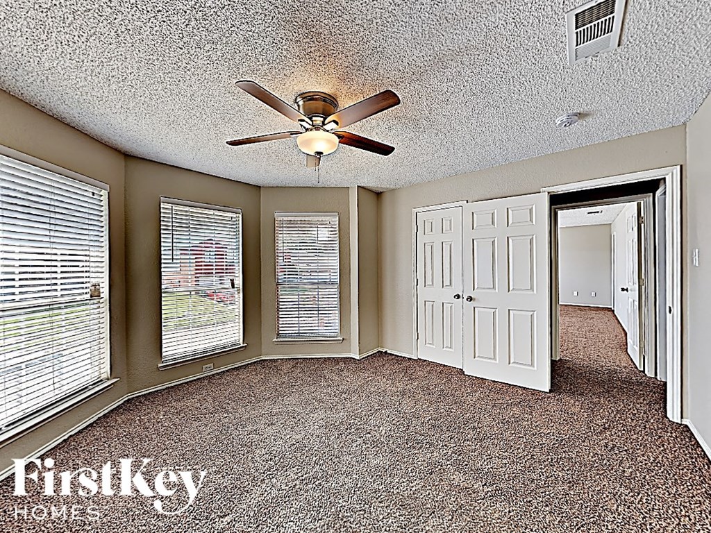 an empty living room with a ceiling fan and a door
