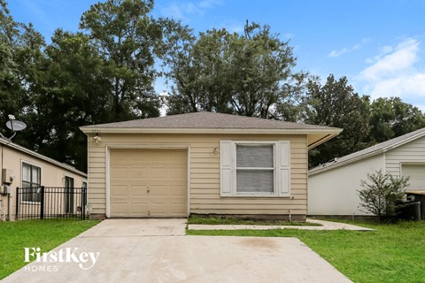 a small tan house with a driveway and a garage door