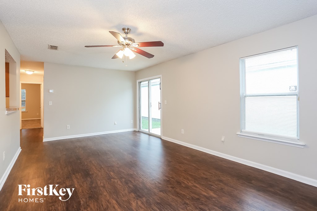 an empty living room with hardwood flooring and a ceiling fan