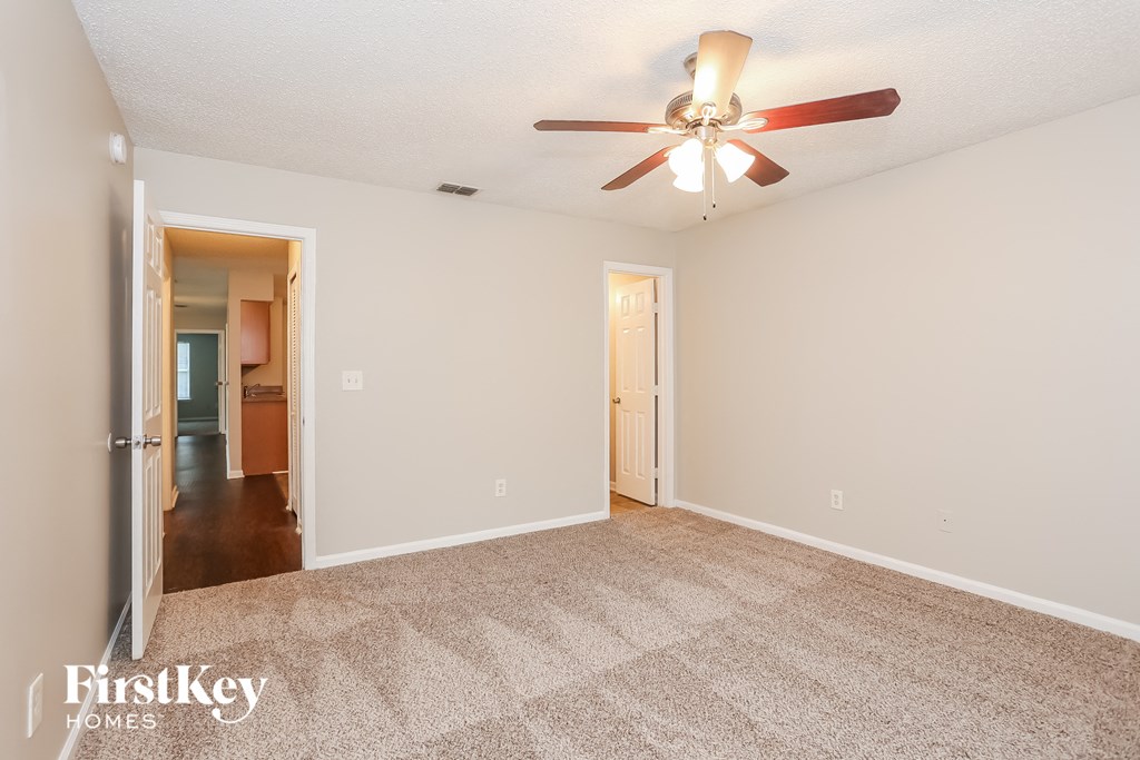 a spacious living room with carpet and a ceiling fan