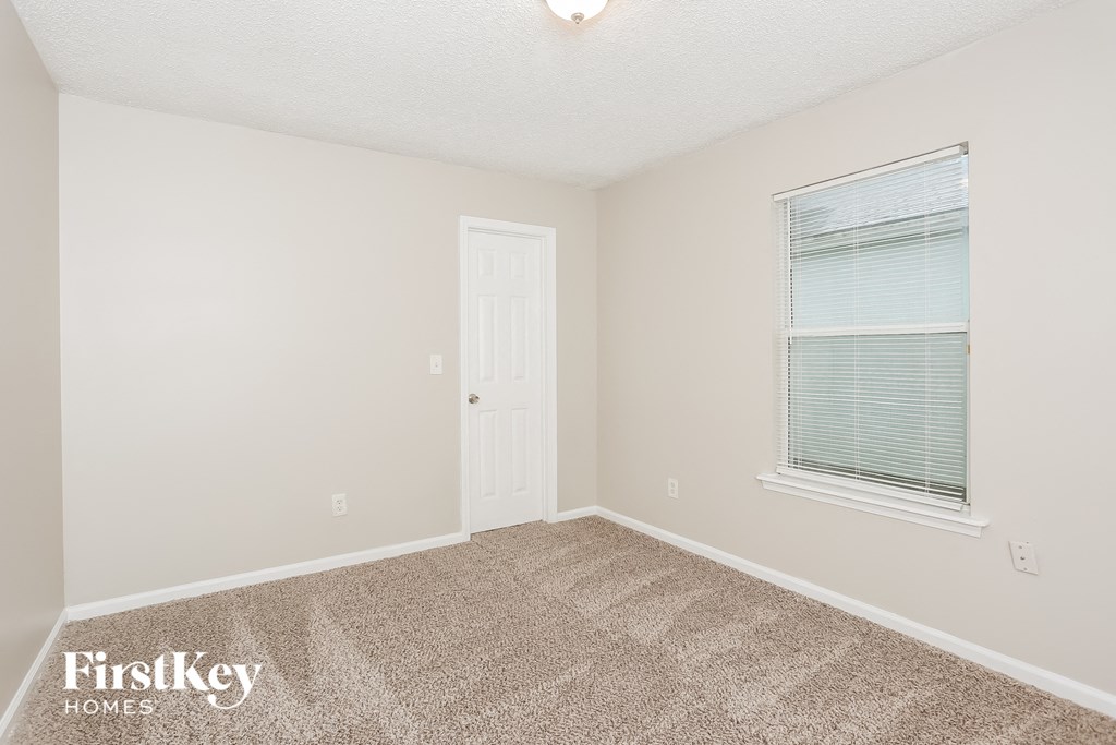 a bedroom with carpet and a window and a door