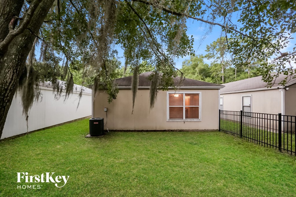 a backyard with a house and a fence and a tree
