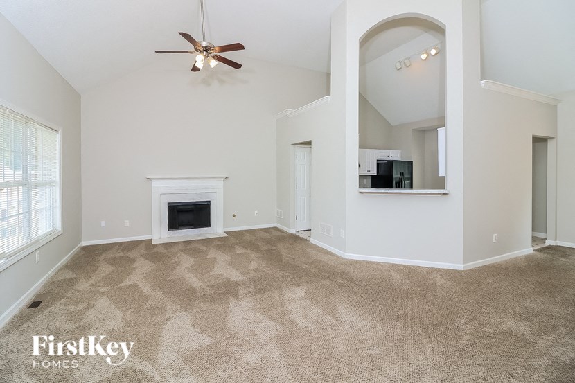 A spacious living room with a fireplace and a fan.