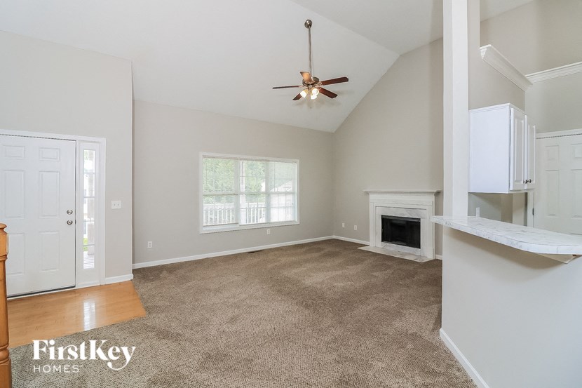 A spacious living room with a fireplace and a ceiling fan.