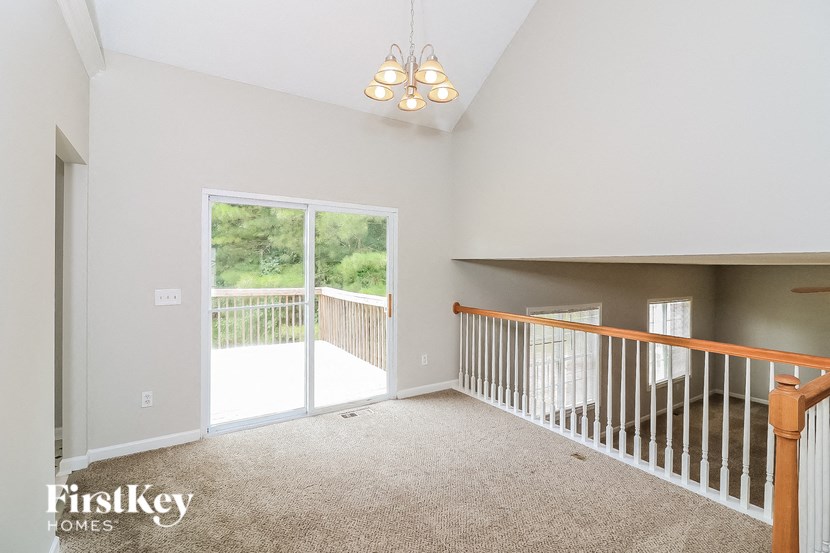A spacious room with a balcony and a carpeted floor.