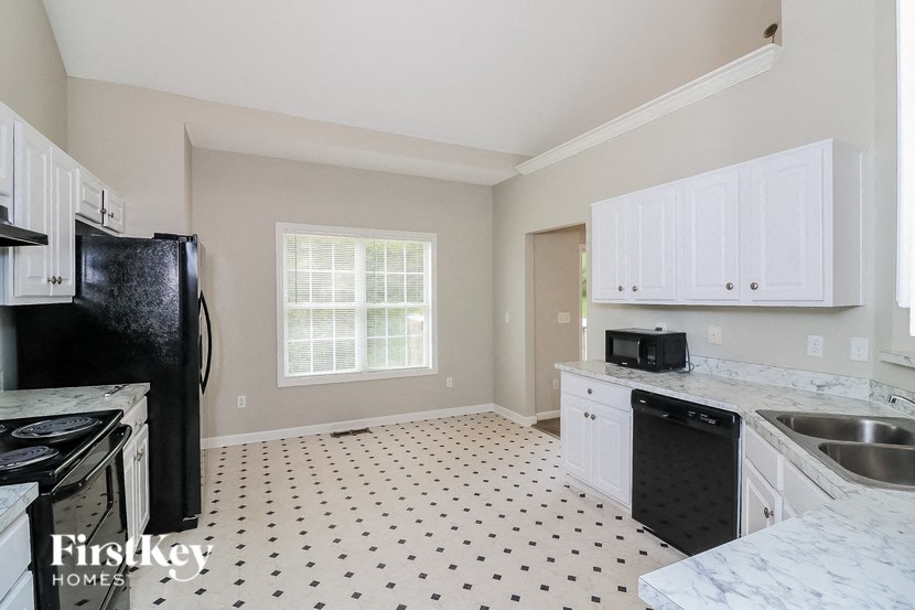 A kitchen with a black fridge and white cabinets.