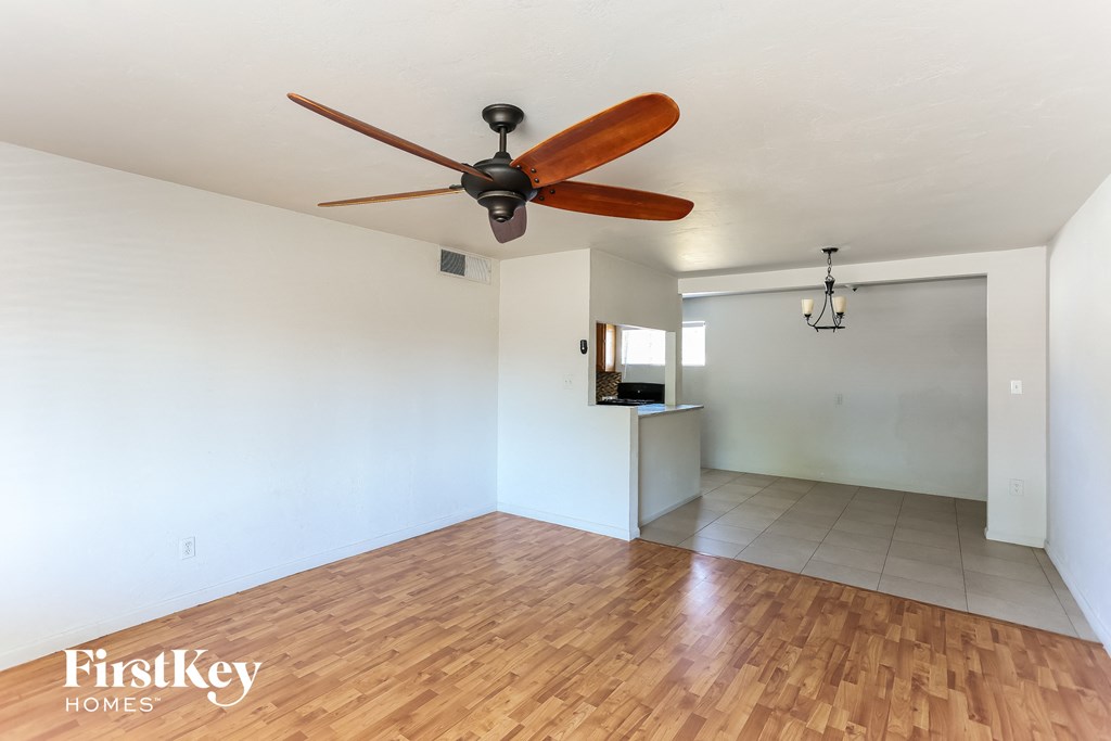 the living room and dining room with wood flooring and a ceiling fan
