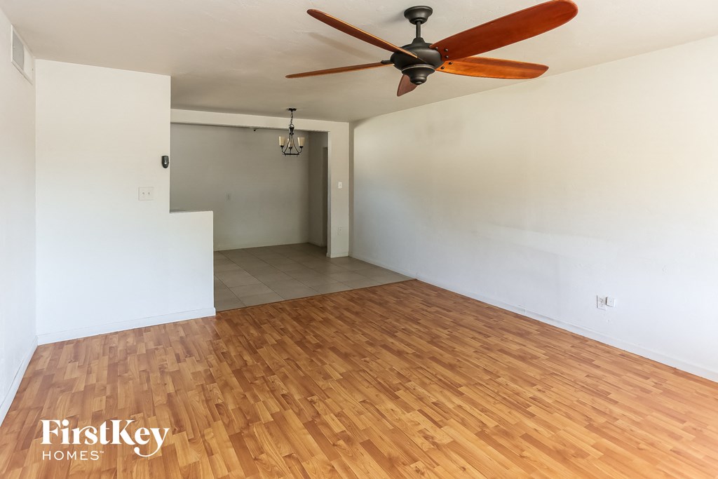 an empty living room with wood floors and a ceiling fan