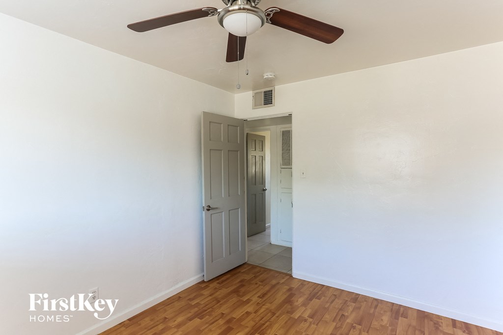 a bedroom with white walls and a ceiling fan