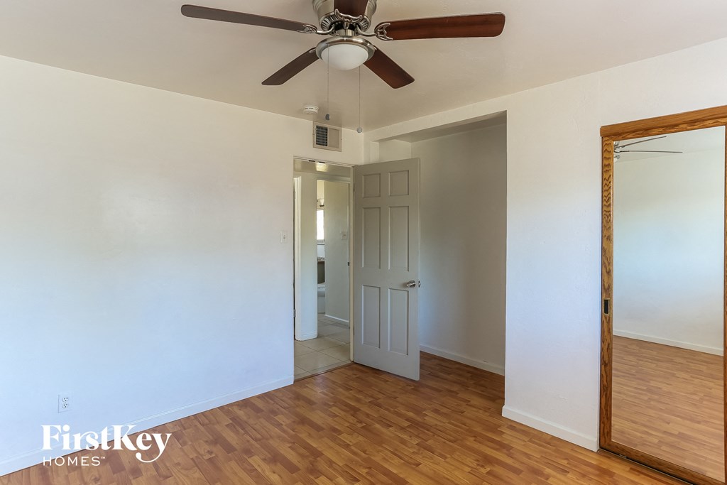 an empty living room with wood floors and a ceiling fan