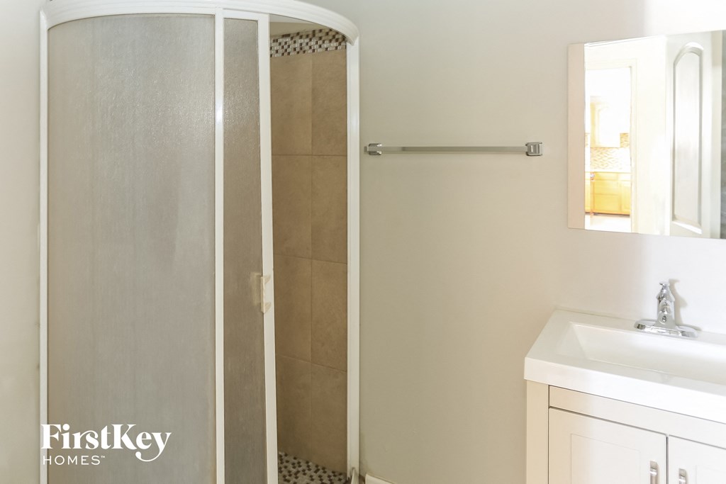 a bathroom with a shower and a sink and a mirror