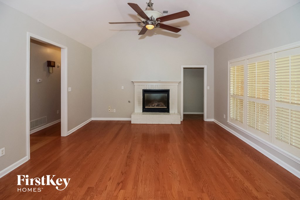 A spacious room with a fireplace and a ceiling fan.