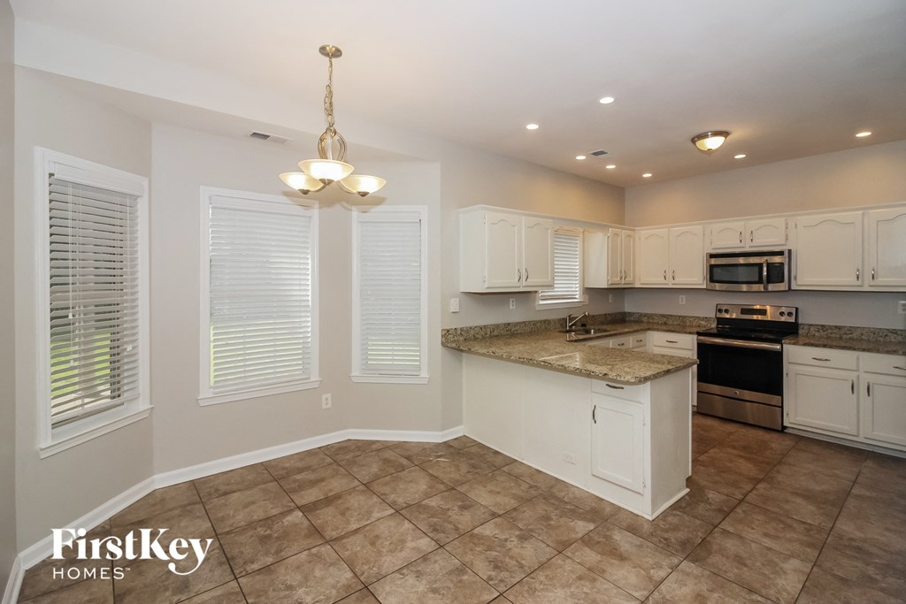 A kitchen with a tile floor and a chandelier hanging from the ceiling.