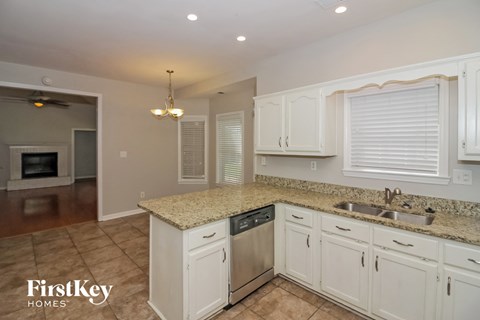 A kitchen with white cabinets and a granite countertop.