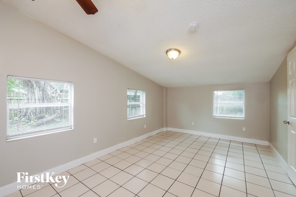 A room with white tiled floors and two windows.