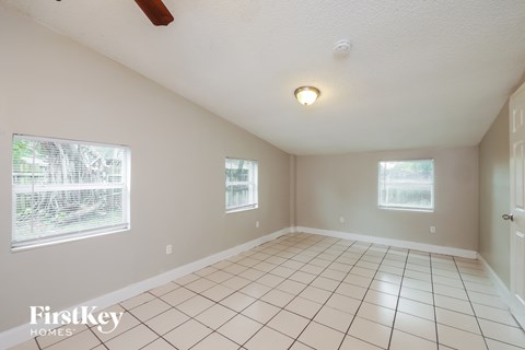 A room with white tiled floors and two windows.