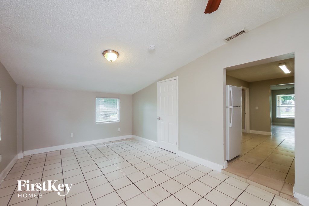 A spacious empty room with a fan and a window.
