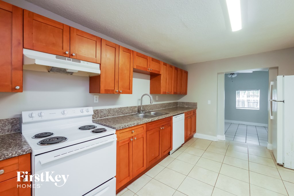 A kitchen with white appliances and orange cabinets.