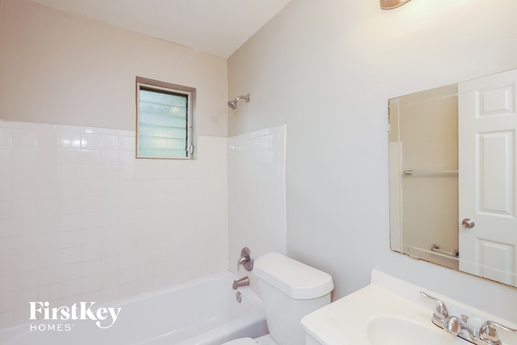 A white bathroom with a tub, toilet and sink.