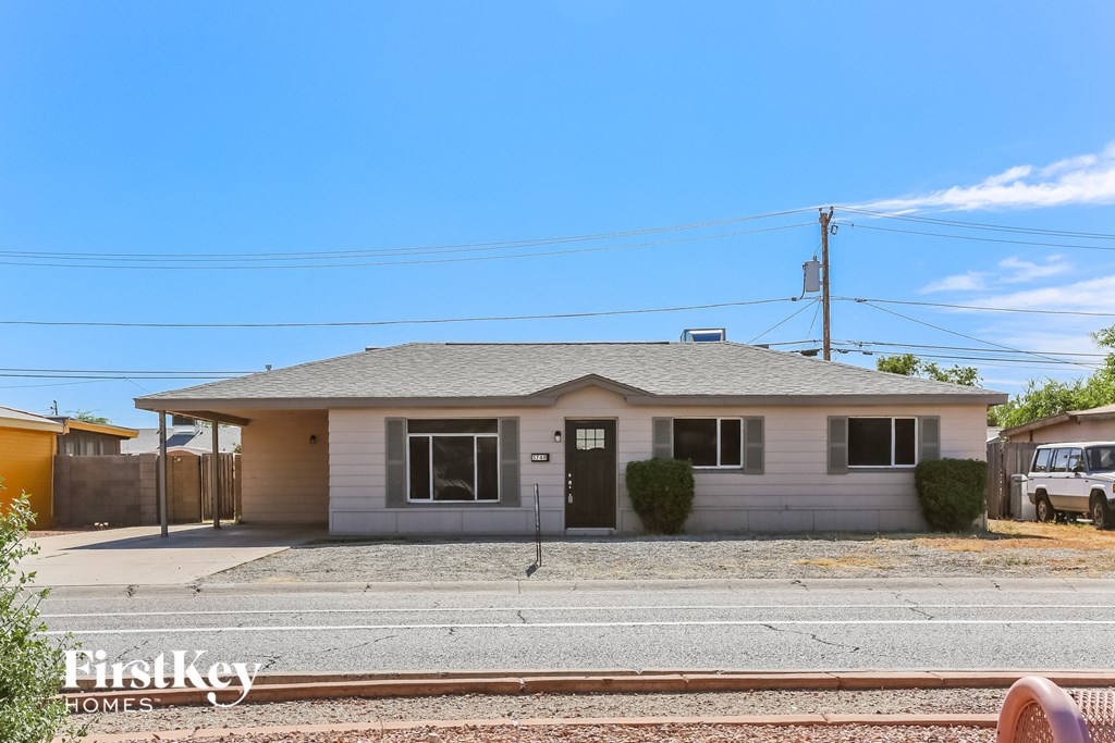 A house with a grey roof and a sign that says "FirstKey Homes" in front of it.