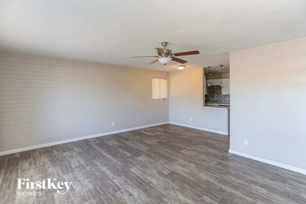 A room with a ceiling fan and wooden flooring.