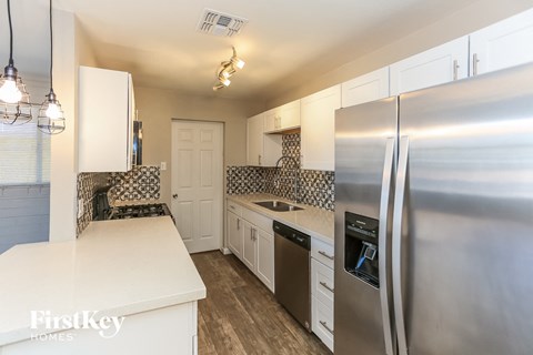 A kitchen with a stainless steel refrigerator and white cabinets.