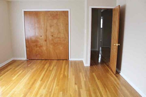 a living room with a wooden floor and a wooden door