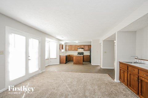 a kitchen and living room with wood cabinets and a rug