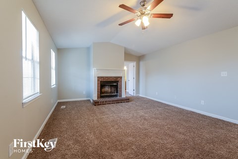 an empty living room with a fireplace and a ceiling fan