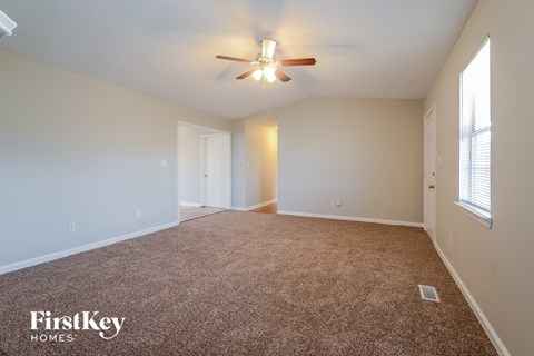a spacious living room with carpet and a ceiling fan
