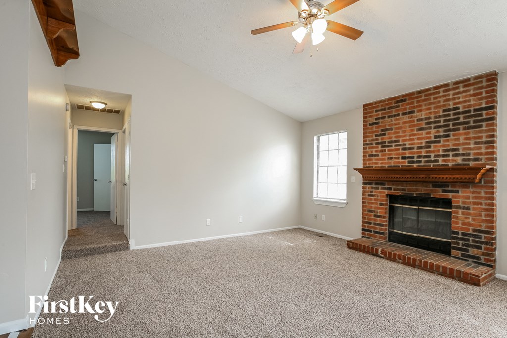 a living room with a brick fireplace and a ceiling fan