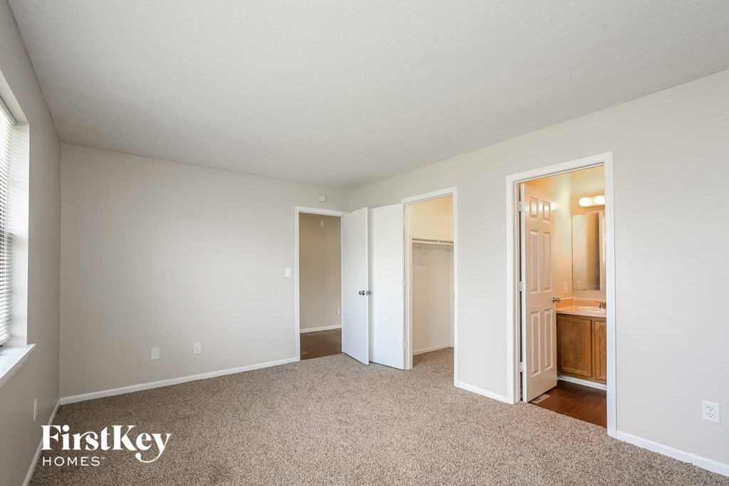 a bedroom with carpet and a door to a bathroom