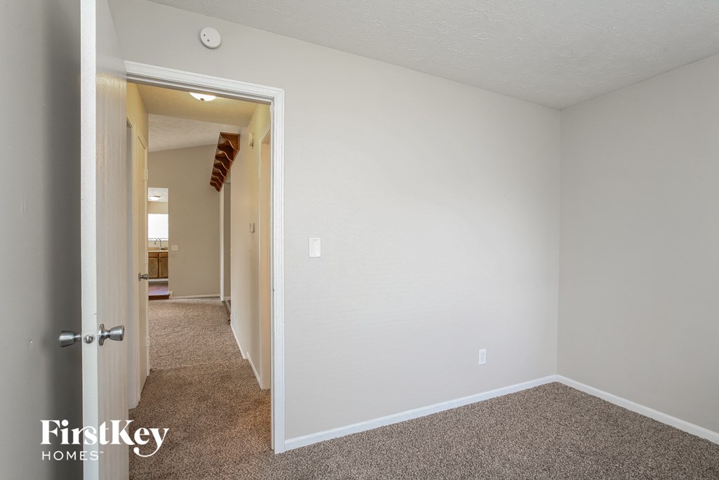 the living room of an apartment with carpet and white walls