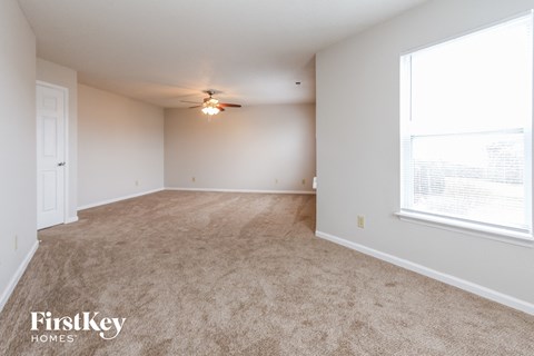 a spacious living room with carpet and a ceiling fan