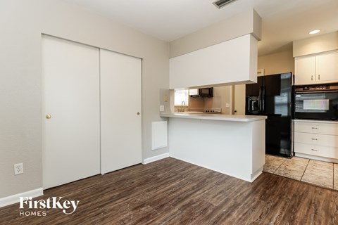 A kitchen with a white counter and a black fridge.