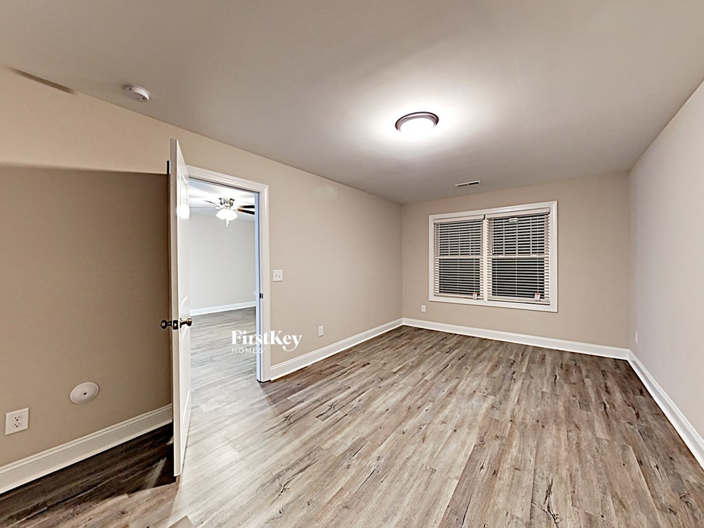 A room with wooden flooring and a window with blinds.