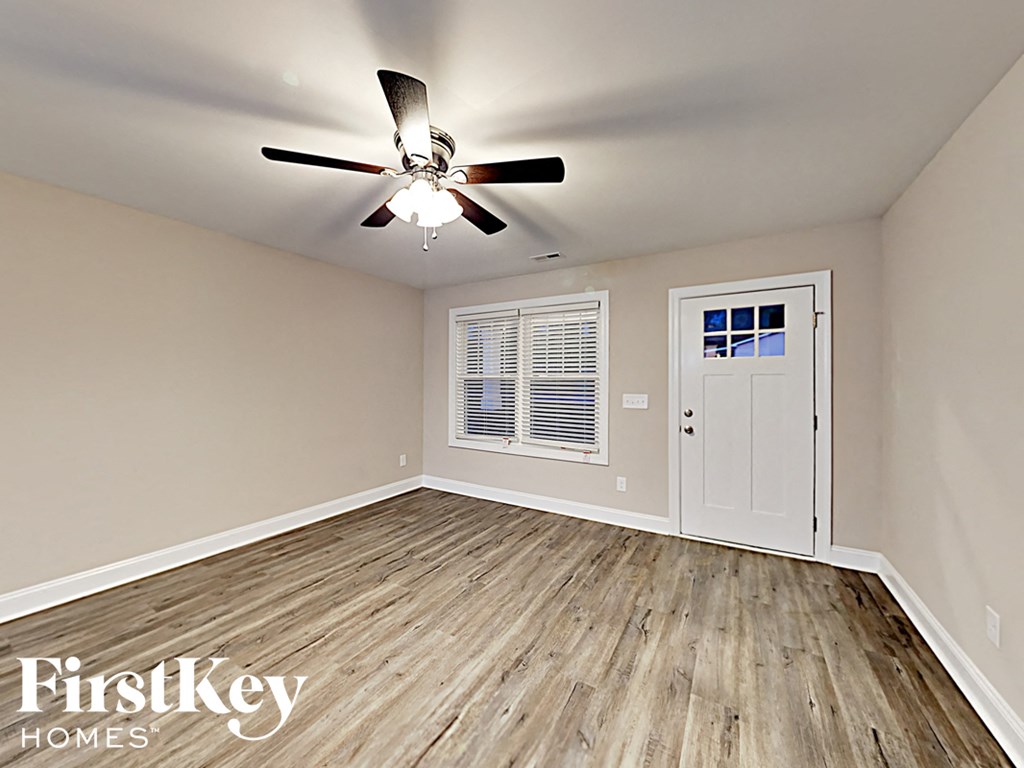 A room with a ceiling fan and wooden flooring.