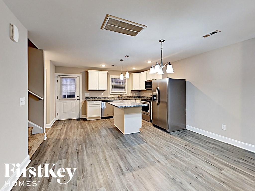 A kitchen with a refrigerator, sink, and cabinets.