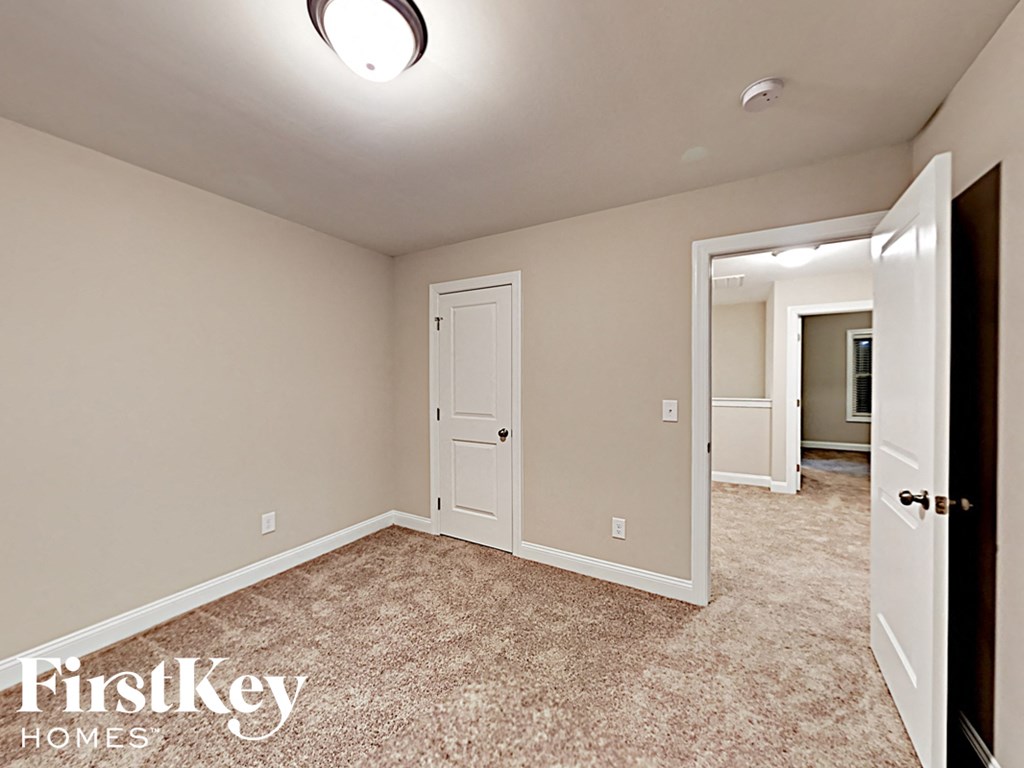 A bedroom with a carpeted floor and a doorway leading to another room.