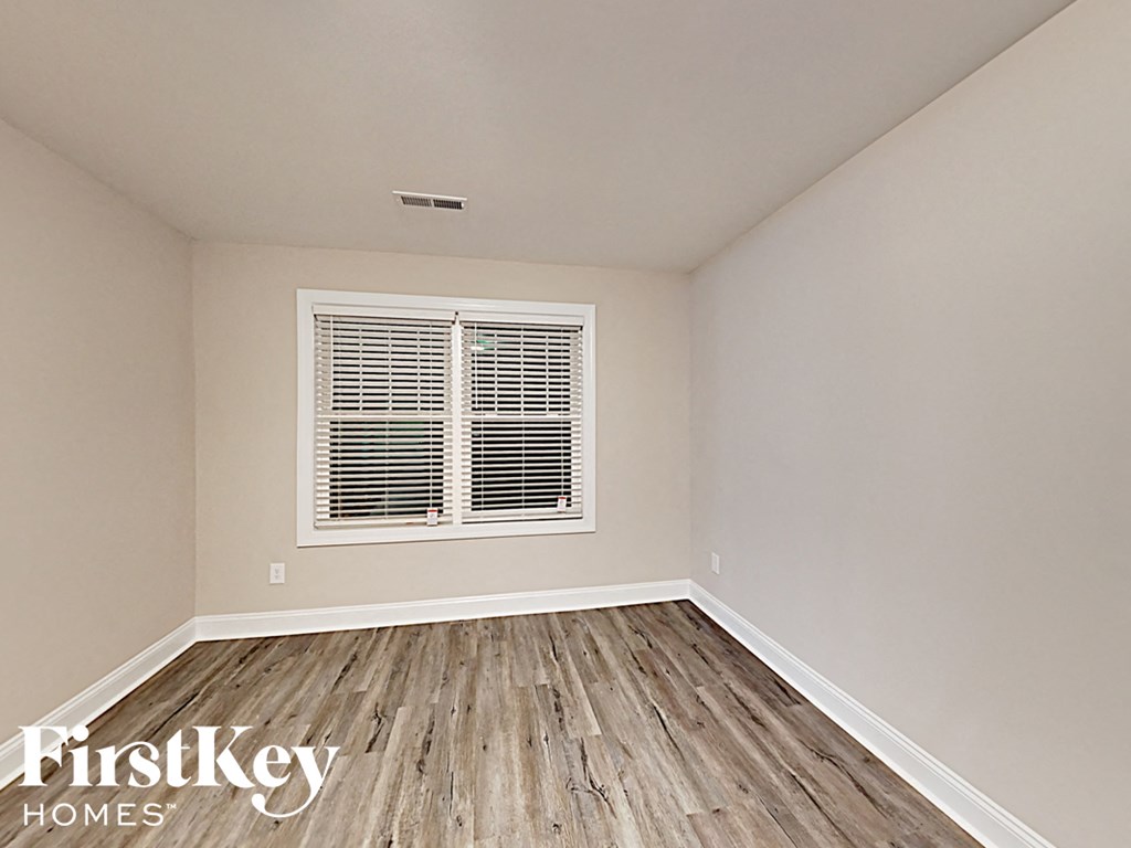 A room with wooden flooring and a window with blinds.