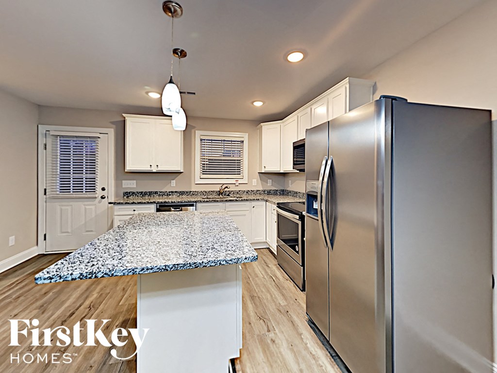 A kitchen with a stainless steel refrigerator and a granite countertop.