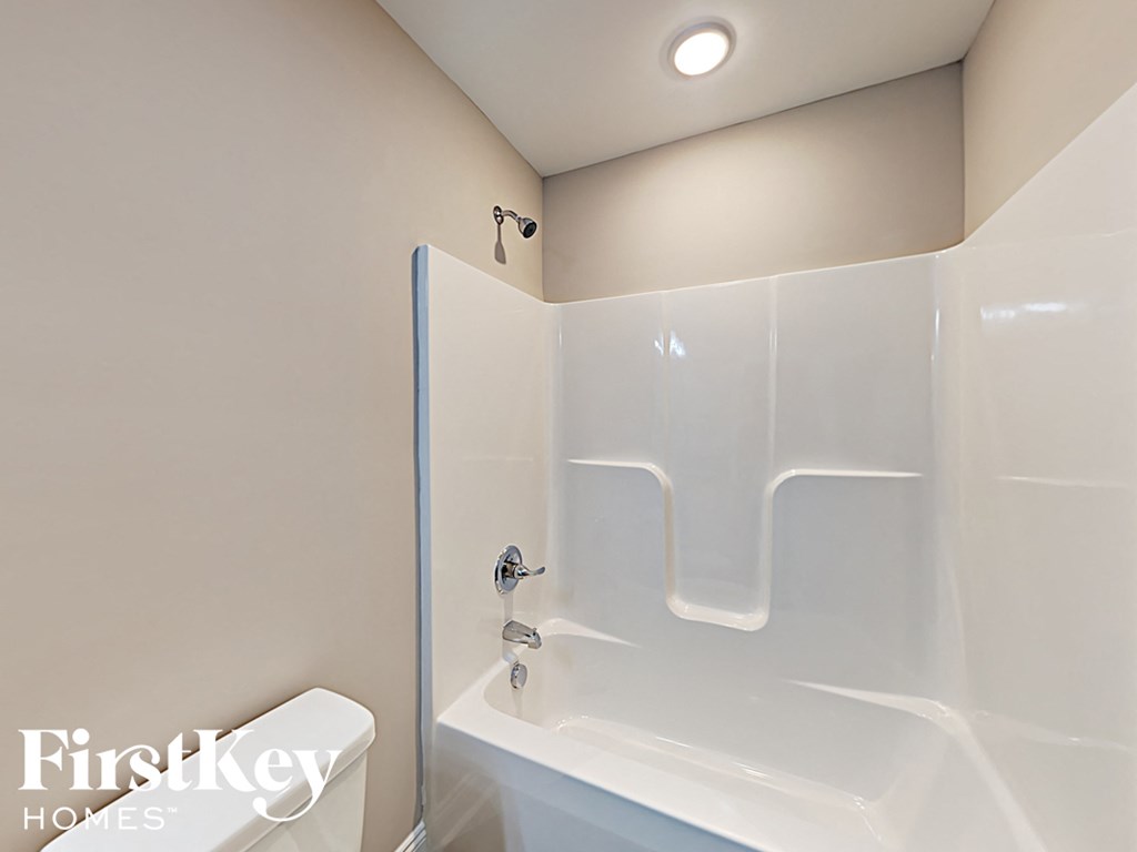 A white bathroom with a walk in shower and a toilet.