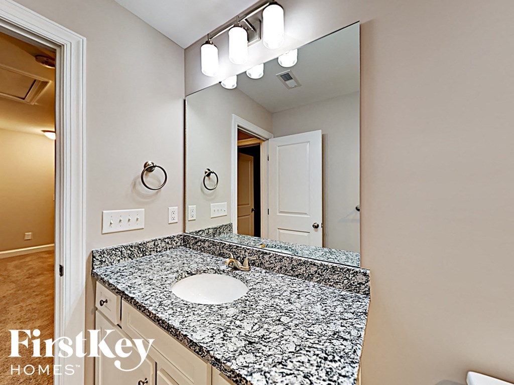 A bathroom with a granite countertop and a large mirror.