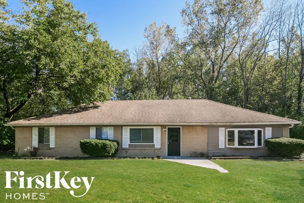 a brown brick house with a lawn and trees