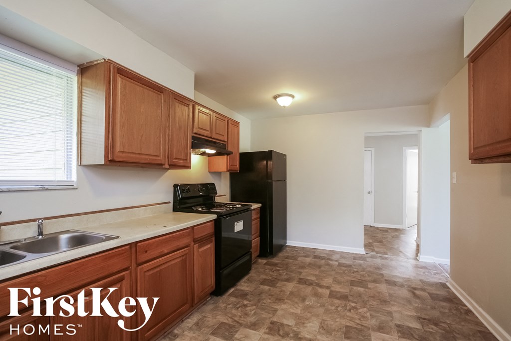 a kitchen with wooden cabinets and a black refrigerator and a sink