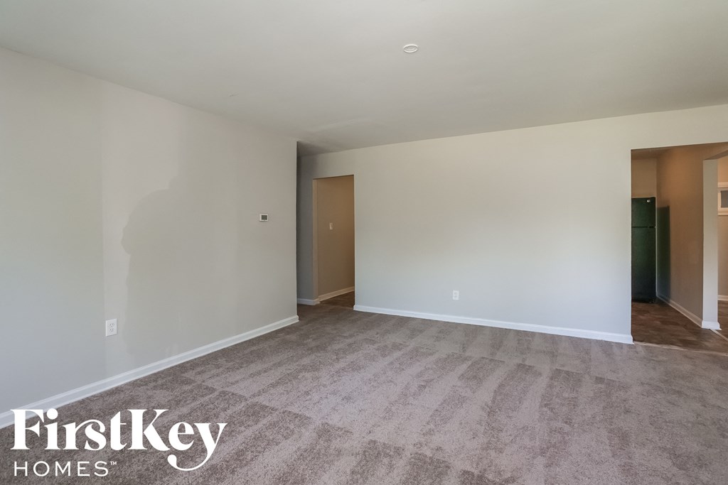 an empty living room with carpet and white walls