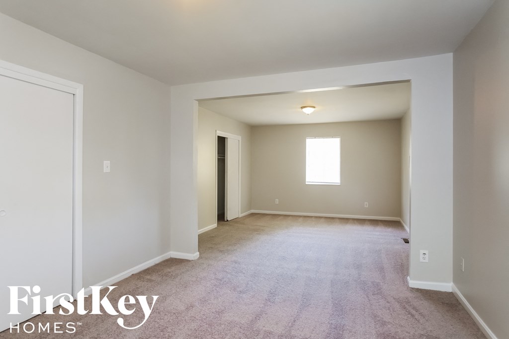 a white carpeted living room with a white door and a window